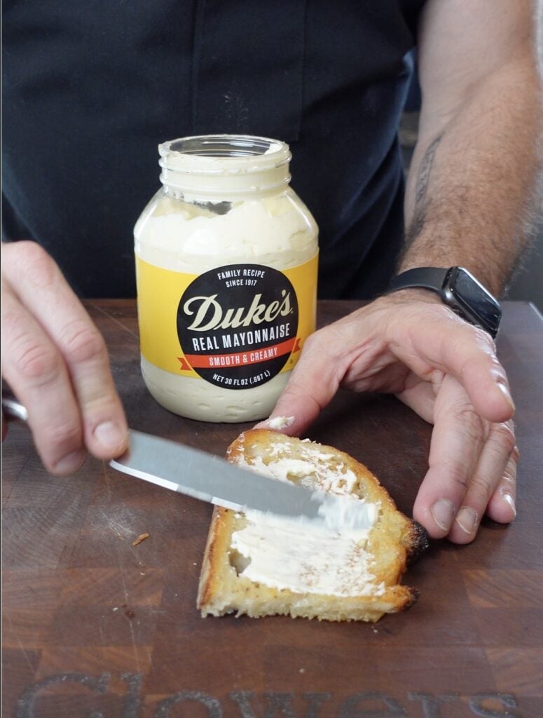 Dukes Mayo spreading onto bread.
